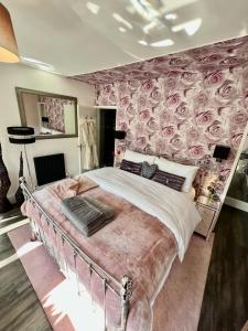 兰戈伦Gamelin的一间卧室配有一张带玫瑰壁纸的大床