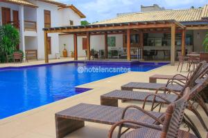 塞古罗港Encantos de Itaperapuã的一个带椅子和房子的游泳池的度假胜地