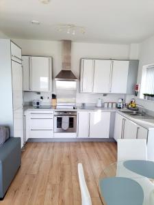 拉内利Coastal apartment with beach on your doorstep!的厨房铺有木地板,配有白色橱柜。