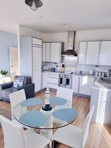 拉内利Coastal apartment with beach on your doorstep!的厨房以及带玻璃桌和椅子的客厅。