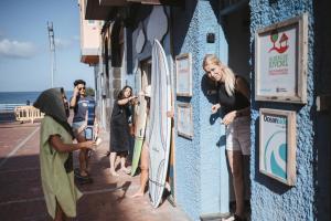 大加那利岛拉斯帕尔马斯La Ventana Azul Surf Hostel的一群人站在一座有冲浪板的建筑外