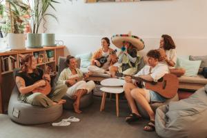 大加那利岛拉斯帕尔马斯La Ventana Azul Surf Hostel的一群坐在客厅里弹吉他的妇女