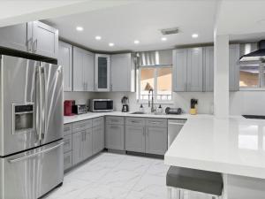 迈阿密花园Modern 4BR2 HEATED POOL GRILL Big backyard的厨房配有白色橱柜和不锈钢冰箱
