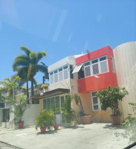圣胡安Cozy Beach Apartment的一座红色的建筑,前面有棕榈树