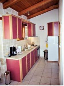 瓦西里科斯Villa Belvedere - Sea view apts near Banana beach的厨房配有红色橱柜和白色冰箱