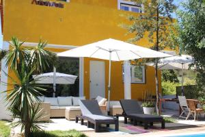 塞图巴尔Casal da Anixa的黄色建筑旁的带椅子和遮阳伞的庭院
