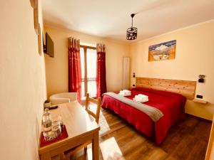 克拉维埃Hotel Piccolo Chalet的一间卧室配有红色的床、一张书桌和窗户。