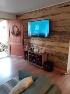 瓦尔迪维亚Cabañas Calihue的客厅设有木墙,配有电视。