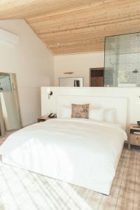 马里布卡拉明哥游客牧场和海滩俱乐部度假村的卧室内的一张白色大床,拥有木制天花板