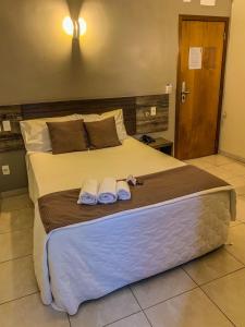 龙多诺波利斯Hotel Piratininga Avenida Amazonas - Rondonópolis的一间卧室配有一张大床和毛巾