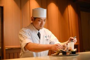 尾道市Onomichi Hansei的一位厨师帽上的人准备一盘食物