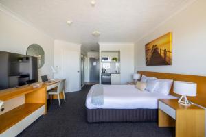 汤斯维尔Aligned Corporate Residences Townsville的配有一张床和一张书桌的酒店客房