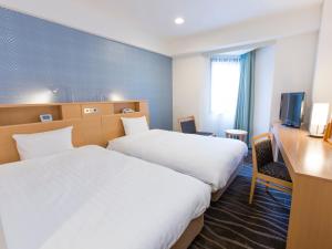 东京涩谷东武酒店的酒店客房设有两张床、一张桌子和一台电视。