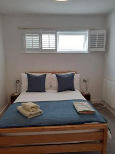 文特诺Wheelers Bay Apartment的一间卧室配有一张带蓝色枕头的床和两个窗户。