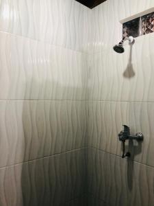 八丹拜Padangbai Beach inn的带淋浴和盥洗盆的白色瓷砖浴室