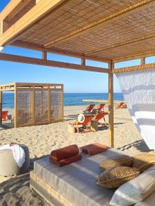 阿德里安诺斯坎波斯拉奎拉里斯马海滩酒店的海滩上的一张床位,配有椅子和海洋