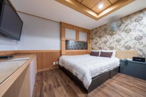 釜山MU Hotel Sasang的一间卧室配有一张床和一台平面电视