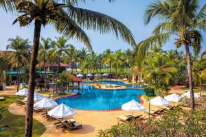 瓦尔恰卡拉维尔海滩度假村的度假村的游泳池拥有棕榈树和遮阳伞