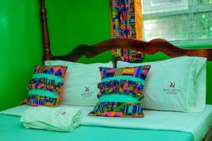 MbaleRichy Hotels and Safaris的一张带色彩缤纷的枕头和绿色墙壁的床