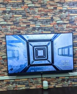 贝宁城Naboya House Serviced Apartment的砖墙上的大屏幕平面电视