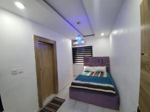 拉各斯Dinero Rose-2 Bedroom Apartment的白色客房内的一间卧室配有一张紫色的床