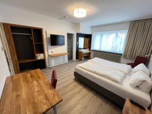 库尔三皇酒店的一间卧室配有一张床、一张桌子和一台电视