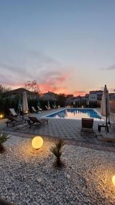 奥赫里德Villa Kotlar的日落时分带椅子和遮阳伞的游泳池