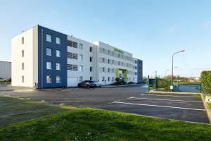 戈内斯B&B HOTEL Paris Nord Gonesse Parc des Expos的停车场,有一座白色的大建筑