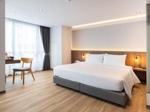 MakkasanPure Eleven Hotel Bangkok的卧室配有一张白色大床和一张书桌