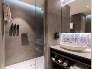 阿姆斯特丹Mercure Amsterdam City Hotel的一间带水槽和玻璃淋浴的浴室