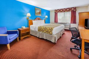佩里斯堡Baymont by Wyndham Perrysburg-Toledo的配有一张床和一把椅子的酒店客房
