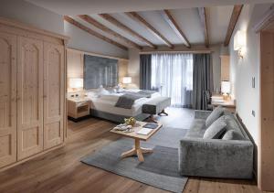 奥蒂塞伊Gardena Grödnerhof - Hotel & Spa的酒店客房,配有床和沙发