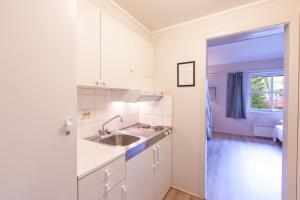TronesNamsskogan Familiepark & Hotell的厨房配有白色橱柜、水槽和窗户。