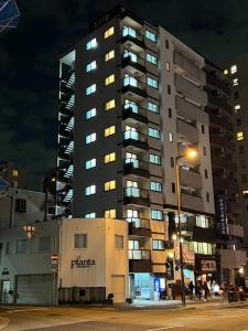 大阪GN98 Saiwaicho Osaka的夜晚高大的公寓楼,有街灯