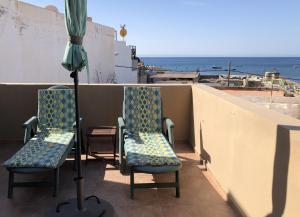 塔拉哈勒赫La casa de la playa的阳台上配有两把椅子和一把遮阳伞,