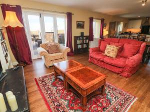 康福斯Langthwaite Cottage的客厅配有红色沙发和茶几