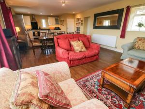 康福斯Langthwaite Cottage的客厅配有红色的沙发和桌子
