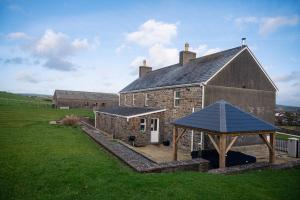 卡马森Castell Y Waun- Beautiful and spacious country farmhouse with luxury Hot Tub & Grounds的一座大型砖砌建筑,前面设有凉亭