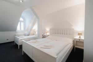 布尔诺多沃拉科瓦酒店的白色卧室配有一张白色的大床和两张桌子