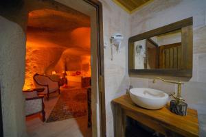内夫谢希尔Babili Cappadocia Cave Hotel的一间带水槽和镜子的浴室以及一间客房