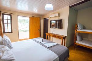 伊利亚贝拉VELINN Pousada Praia do Perequê的一间卧室配有一张床、一张书桌和一个窗户。