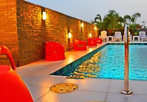 莱卡邦德维拉素万那普酒店的砖墙旁的游泳池,配有红色椅子