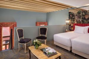 威尼斯NH Collection Grand Hotel Palazzo Dei Dogi的一间卧室配有一张床铺、椅子和一张桌子