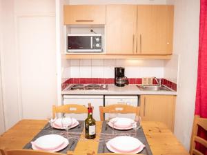 皮伊圣万桑Appartement Puy-Saint-Vincent, 3 pièces, 6 personnes - FR-1-504-184的厨房配有带盘子的桌子和一瓶葡萄酒