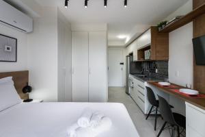 圣保罗Studio com lazer e varanda no Alto da Boa Vista的白色卧室设有白色的床和厨房