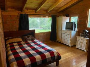 昆卡Casa de campo rústica en Cuenca的小屋内一间卧室配有一张床和电视