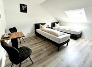 伦讷施塔特拉尔曼兰德酒店的配有一张桌子和一把椅子的客房内的两张床