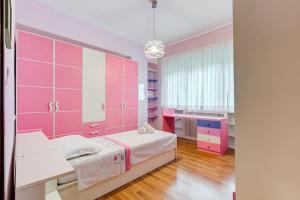 罗马Exclusive Apartment in Eur Lake的粉红色的卧室配有一张床和一张书桌