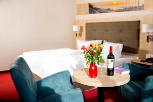 塞巴特阿尔贝克Hotel Garni Sonne的酒店客房带一张桌子,还有一瓶葡萄酒和鲜花
