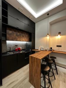 马德里CC Atocha Apartments的厨房配有黑色橱柜和带酒吧凳的木制岛屿